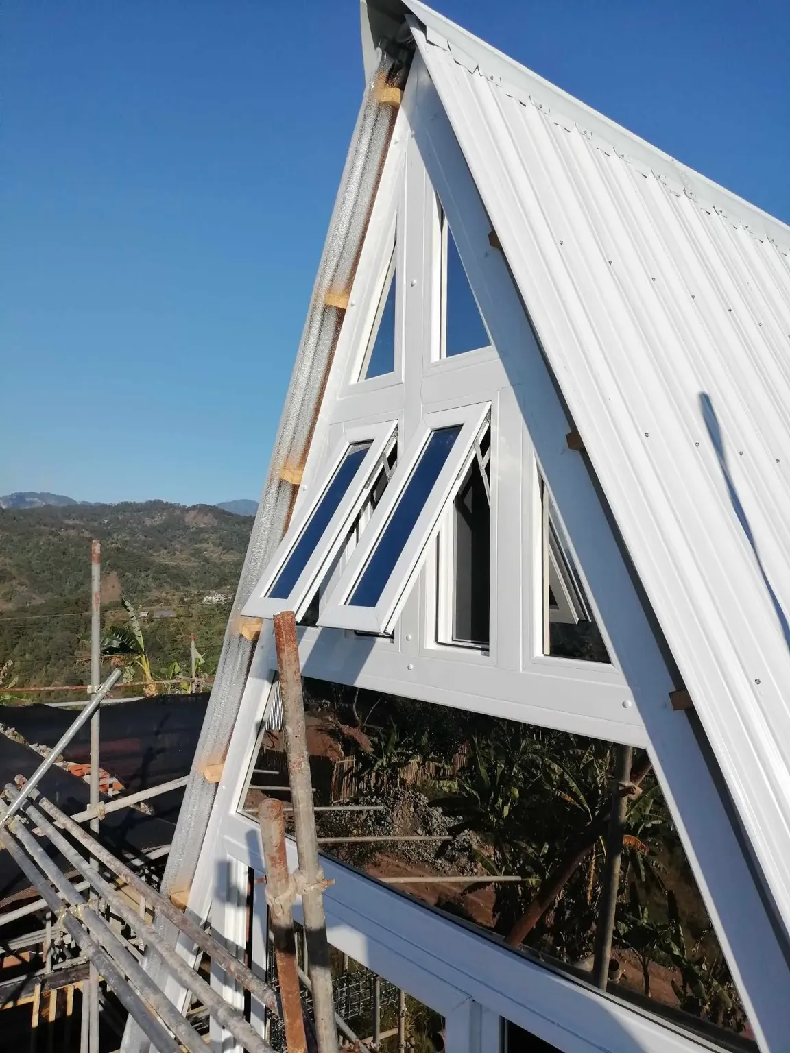Outside view of a house's roof with white-framed uPVC awning windows and reflective glass.